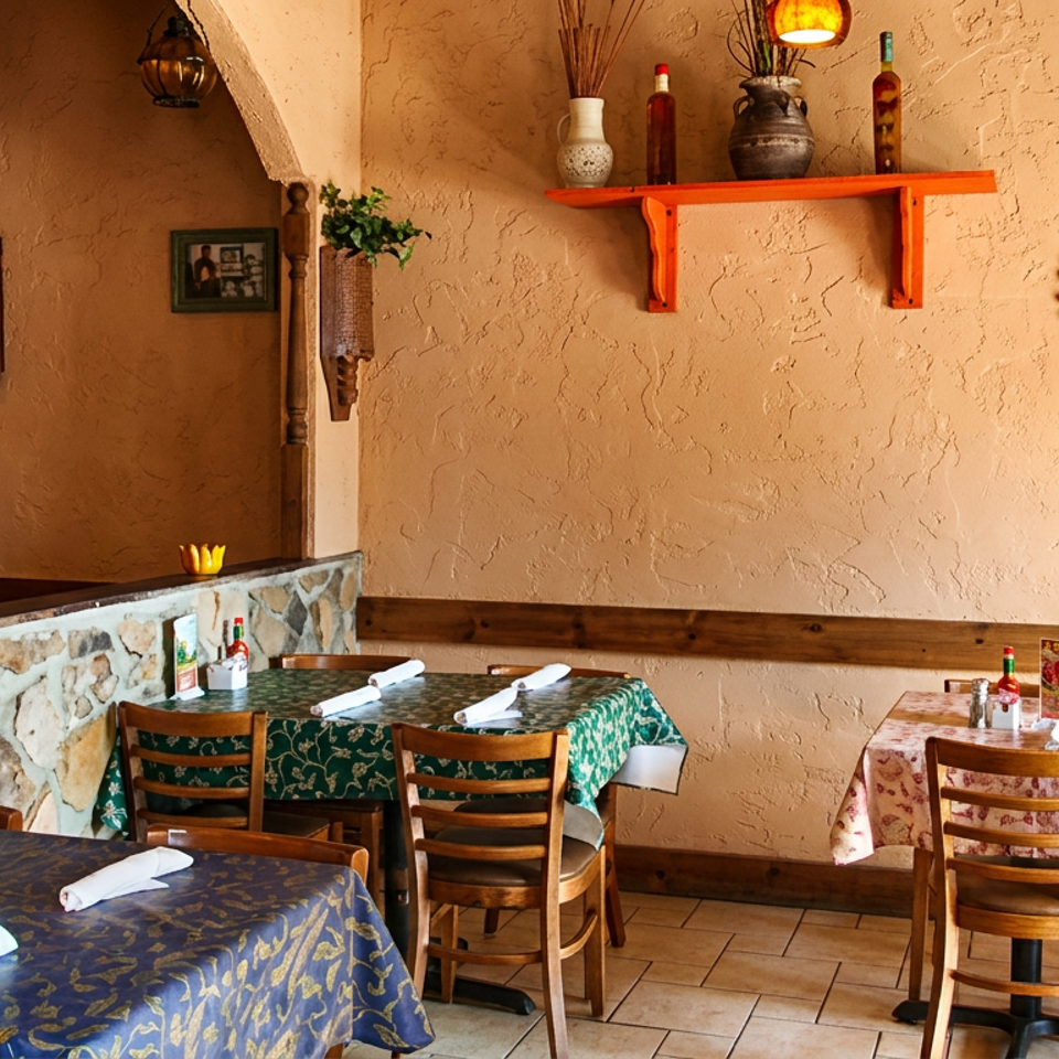 Warmly lit restaurant dining room with patterned tablecloths, set tables, rustic décor, and textured stucco walls.